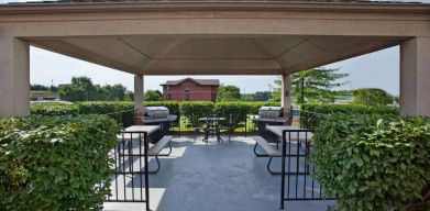 Sonesta Simply Suites Pittsburgh Airport’s gazebo features seating and tables outdoors and under cover, with two barbecues and a surrounding hedge.