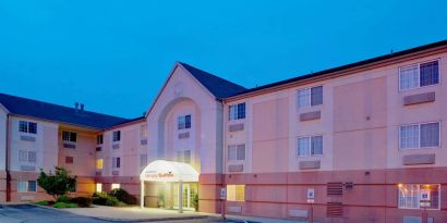 Sonesta Simply Suites Pittsburgh Airport’s exterior includes a covered entrance, pleasant greenery, and parking spaces.