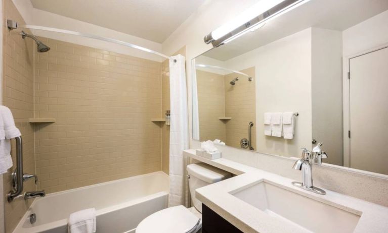 Guest bathroom in Sonesta Simply Suites Detroit Ann Arbor, which is furnished with shower-equipped bath, mirror and sink, and a lavatory.