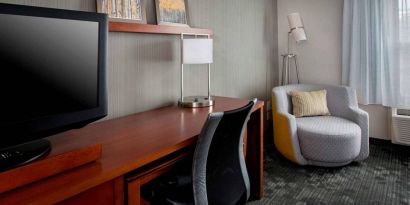 Sonesta Select Tinton Falls Eatontown guest room workspace, with desk, chair, and lamp, and TV.