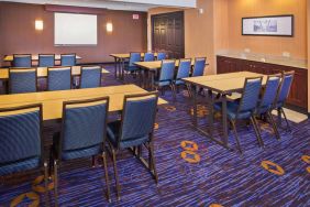 Meeting room in Sonesta Select Tinton Falls Eatontown, with tables arranged in a classroom format facing a projector screen.