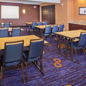 Meeting room in Sonesta Select Tinton Falls Eatontown, with tables arranged in a classroom format facing a projector screen.