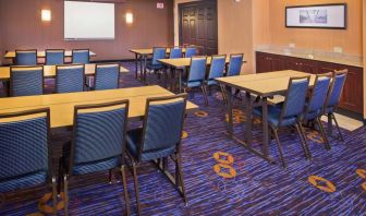 Meeting room in Sonesta Select Tinton Falls Eatontown, with tables arranged in a classroom format facing a projector screen.