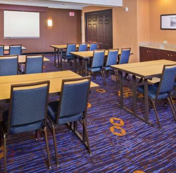 Meeting room in Sonesta Select Tinton Falls Eatontown, with tables arranged in a classroom format facing a projector screen.