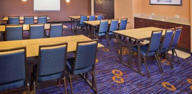 Meeting room in Sonesta Select Tinton Falls Eatontown, with tables arranged in a classroom format facing a projector screen.