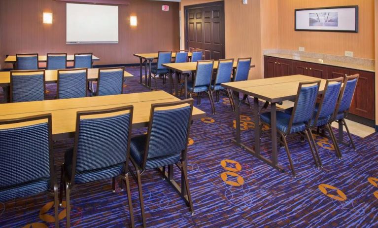 Meeting room in Sonesta Select Tinton Falls Eatontown, with tables arranged in a classroom format facing a projector screen.