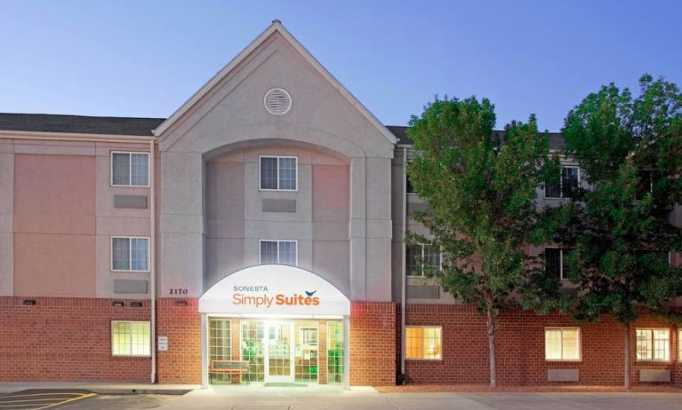 The hotel’s exterior has parking for guests on one side of the covered entrance, and trees to the other side.