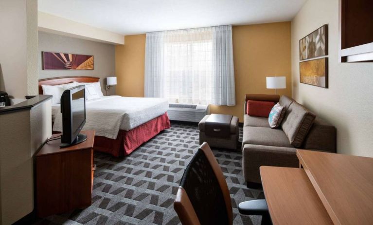 Sonesta Simply Suites Seattle Renton double bed guest room lounge, including sofa, TV, chair, and window.