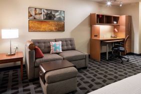 Guest room workspace in Sonesta Simply Suites Seattle Renton, featuring desk, lamp, and chair, with nearby sofa.