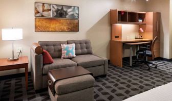 Guest room workspace in Sonesta Simply Suites Seattle Renton, featuring desk, lamp, and chair, with nearby sofa.