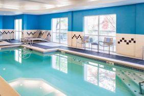 The indoor pool at Sonesta Select Seattle Renton features large windows, and has both chairs and loungers by the side.