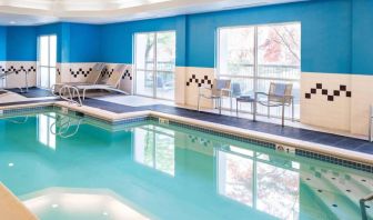 The indoor pool at Sonesta Select Seattle Renton features large windows, and has both chairs and loungers by the side.