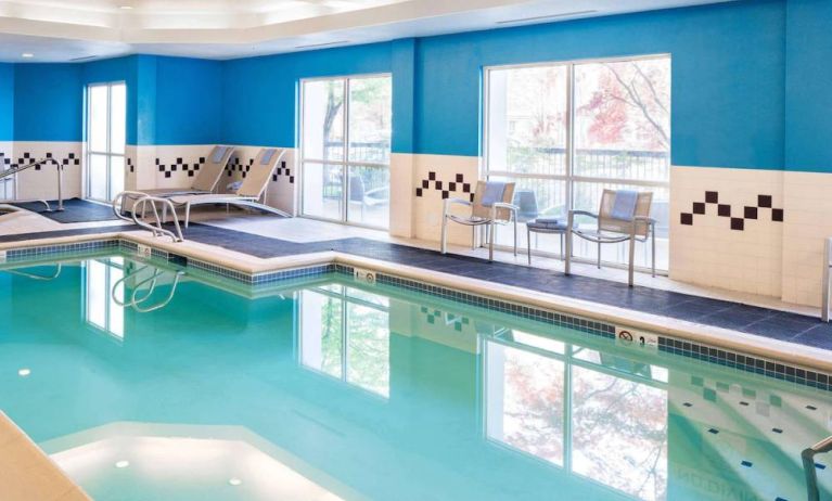 The indoor pool at Sonesta Select Seattle Renton features large windows, and has both chairs and loungers by the side.