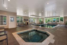 Sonesta ES Suites Parsippany Morris Plains’ indoor pool has a hot tub nearby, chairs and sun loungers nearby, and large windows.