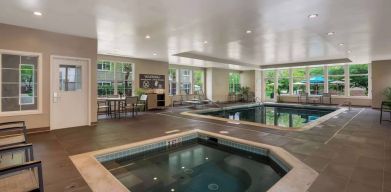 Sonesta ES Suites Parsippany Morris Plains’ indoor pool has a hot tub nearby, chairs and sun loungers nearby, and large windows.