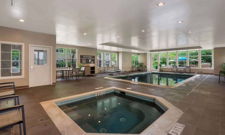 Sonesta ES Suites Parsippany Morris Plains’ indoor pool has a hot tub nearby, chairs and sun loungers nearby, and large windows.