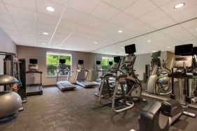 The fitness center in Sonesta ES Suites Parsippany Morris Plains has windows with green views and a wide range of exercise machines.