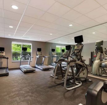 The fitness center in Sonesta ES Suites Parsippany Morris Plains has windows with green views and a wide range of exercise machines.