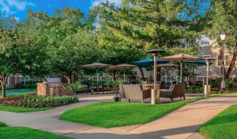 Sonesta ES Suites Parsippany Morris Plains’ barbecue area is furnished with tables and chairs, plus armchair seating, amid numerous trees.