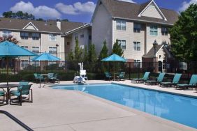 The outdoor pool of Sonesta ES Suites Birmingham Homewood is equipped with a lift, and both sun loungers and shaded tables/chairs are in the vicinity.