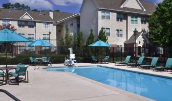 The outdoor pool of Sonesta ES Suites Birmingham Homewood is equipped with a lift, and both sun loungers and shaded tables/chairs are in the vicinity.