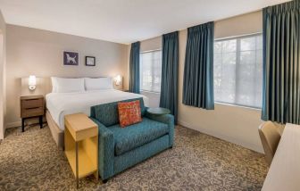 Sonesta ES Suites Andover Boston double bed guest room, including sofa, coffee table, and two windows.