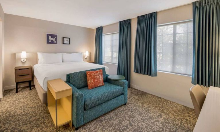 Sonesta ES Suites Andover Boston double bed guest room, including sofa, coffee table, and two windows.