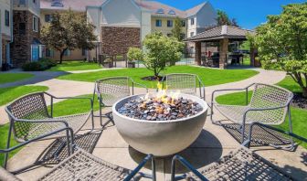 Sonesta ES Suites Andover Boston’s fire-pit is located amid pleasant greenery and surrounded by chairs, with the gazebo and barbecue facilities nearby.