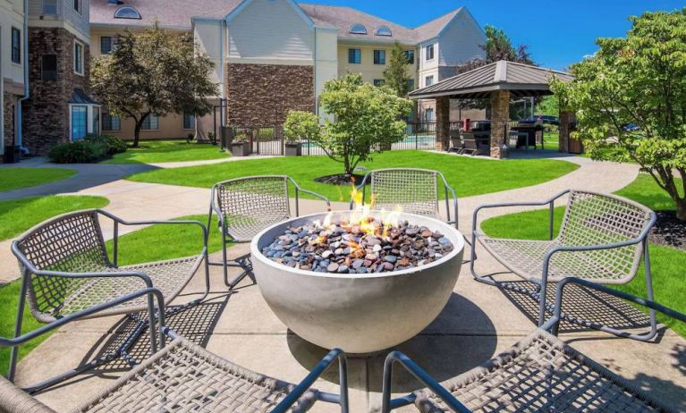 Sonesta ES Suites Andover Boston’s fire-pit is located amid pleasant greenery and surrounded by chairs, with the gazebo and barbecue facilities nearby.