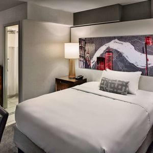 Sonesta Philadelphia Rittenhouse Square double bed guest room, featuring art on the wall, chair, and ensuite bathroom.