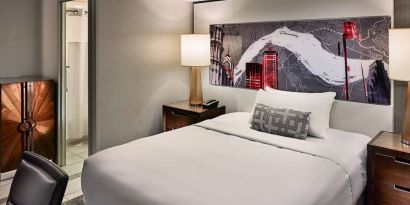 Sonesta Philadelphia Rittenhouse Square double bed guest room, featuring art on the wall, chair, and ensuite bathroom.