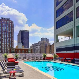 Sonesta Philadelphia Rittenhouse Square’s rooftop pool has sun loungers, armchairs, and potted plants by the side, addition to shaded seating.