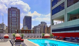 Sonesta Philadelphia Rittenhouse Square’s rooftop pool has sun loungers, armchairs, and potted plants by the side, addition to shaded seating.