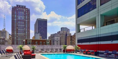 Sonesta Philadelphia Rittenhouse Square’s rooftop pool has sun loungers, armchairs, and potted plants by the side, addition to shaded seating.