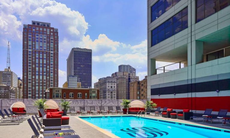 Sonesta Philadelphia Rittenhouse Square’s rooftop pool has sun loungers, armchairs, and potted plants by the side, addition to shaded seating.