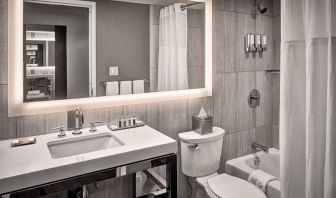 Guest bathroom in Sonesta Philadelphia Rittenhouse Square, equipped with sink and large mirror, lavatory, and bath with a shower.