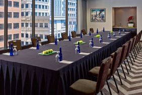 Sonesta Philadelphia Rittenhouse Square meeting room, featuring long table with space for over a dozen attendees, city views through the large windows, and art on the wall.