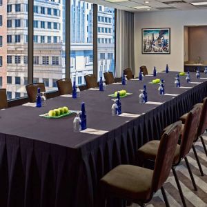 Sonesta Philadelphia Rittenhouse Square meeting room, featuring long table with space for over a dozen attendees, city views through the large windows, and art on the wall.