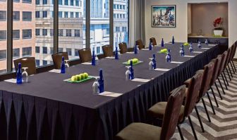 Sonesta Philadelphia Rittenhouse Square meeting room, featuring long table with space for over a dozen attendees, city views through the large windows, and art on the wall.