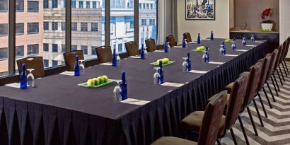 Sonesta Philadelphia Rittenhouse Square meeting room, featuring long table with space for over a dozen attendees, city views through the large windows, and art on the wall.