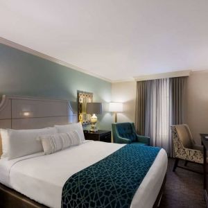 Double bed guest room in Royal Sonesta New Orleans, featuring television, armchair, and a workspace desk and chair.