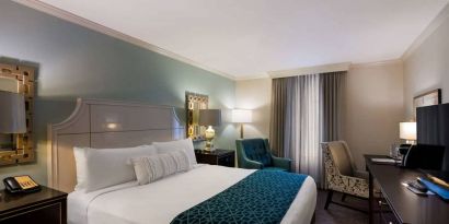 Double bed guest room in Royal Sonesta New Orleans, featuring television, armchair, and a workspace desk and chair.