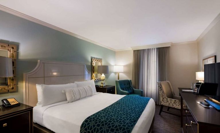 Double bed guest room in Royal Sonesta New Orleans, featuring television, armchair, and a workspace desk and chair.