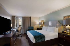 Royal Sonesta New Orleans double bed guest room, furnished with armchairs, desk, and a television.