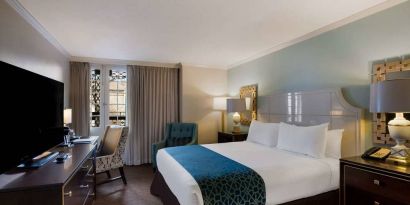 Royal Sonesta New Orleans double bed guest room, furnished with armchairs, desk, and a television.