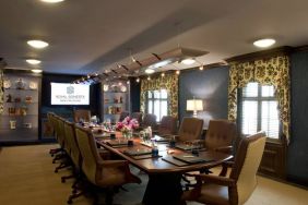 Meeting room in Royal Sonesta New Orleans, furnished with long wooden table, 14 swivel chairs, a widescreen TV, and two windows.