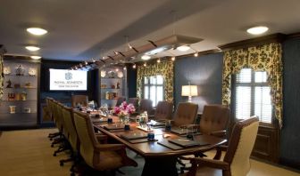 Meeting room in Royal Sonesta New Orleans, furnished with long wooden table, 14 swivel chairs, a widescreen TV, and two windows.