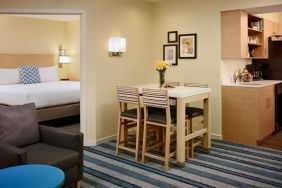 Double bed guest room in Sonesta ES Suites Atlanta - Perimeter Center North, furnished with dining table and four tall stools, with an armchair nearby.