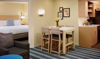 Double bed guest room in Sonesta ES Suites Atlanta - Perimeter Center North, furnished with dining table and four tall stools, with an armchair nearby.