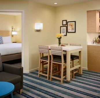 Double bed guest room in Sonesta ES Suites Atlanta - Perimeter Center North, furnished with dining table and four tall stools, with an armchair nearby.